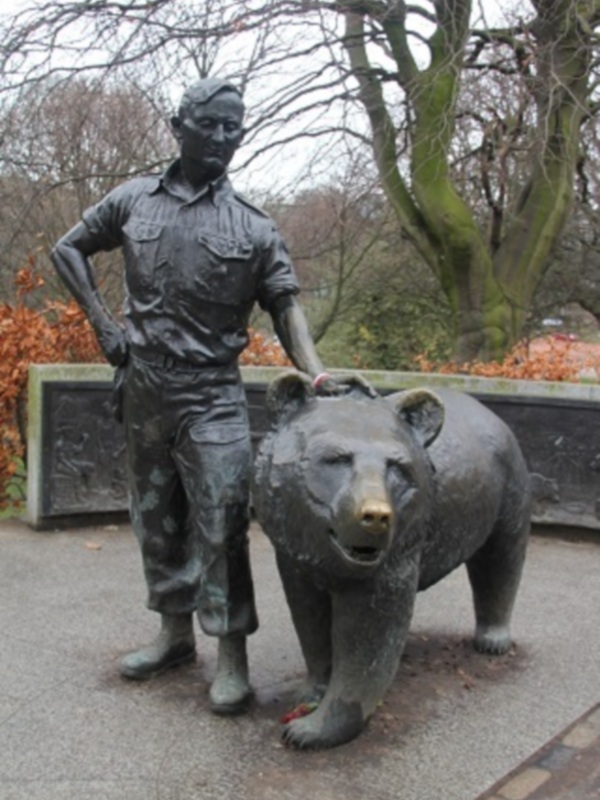 Estatua de un hombre y un oso en un parque o jardín.