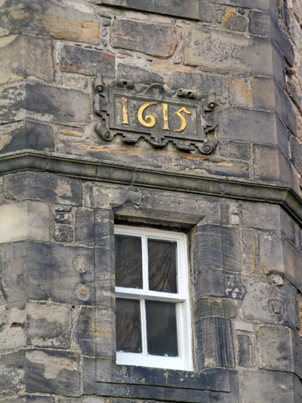 Detalle de una ventana con números en la fachada de piedra antigua, fecha 1615.