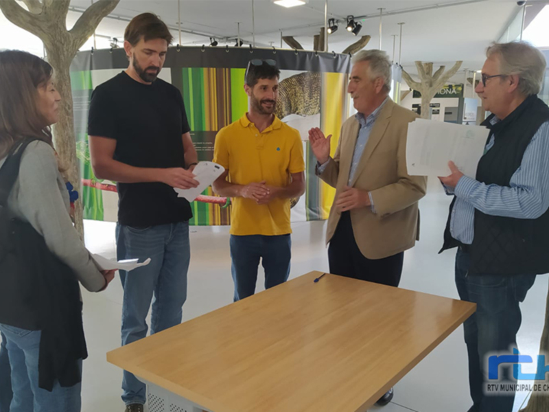 Una reunión formal en un espacio moderno, con personas intercambiando documentos y conversando. La atmósfera es profesional y productiva.