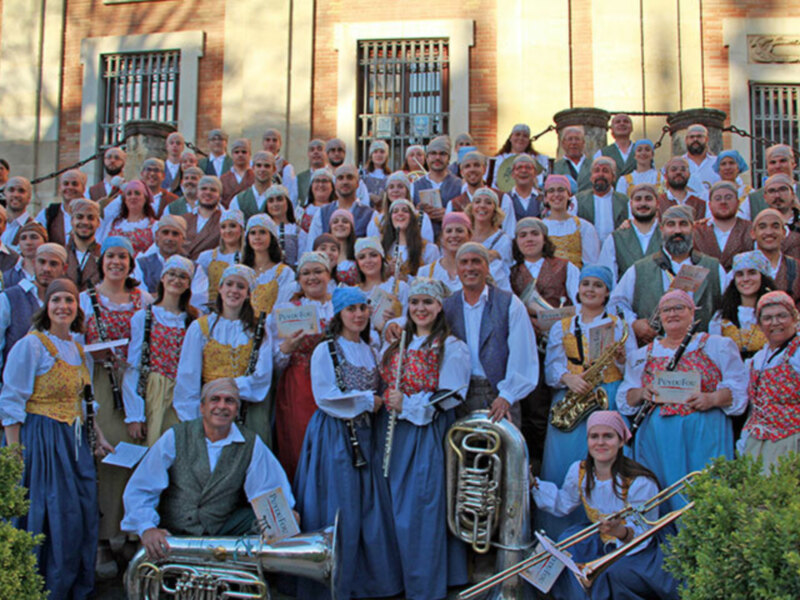 Gente vestida con trajes tradicionales posando para una foto frente a un edificio histórico.