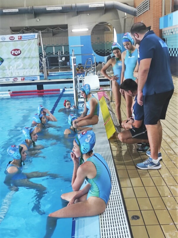 Niños de natación en un club de natación, con un entrenador observando y dando instrucciones.