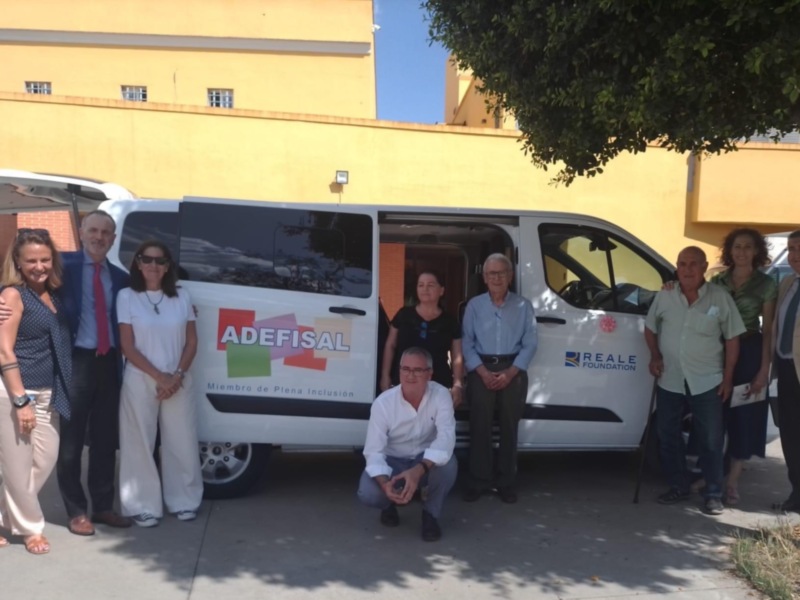 Grupos de personas posan frente a un vehículo blanco con la marca "ADEFISAL" y "REALE". El contexto sugiere una reunión o evento empresarial.