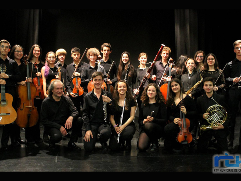 Grupo de músicos en un escenario, posando con instrumentos musicales.