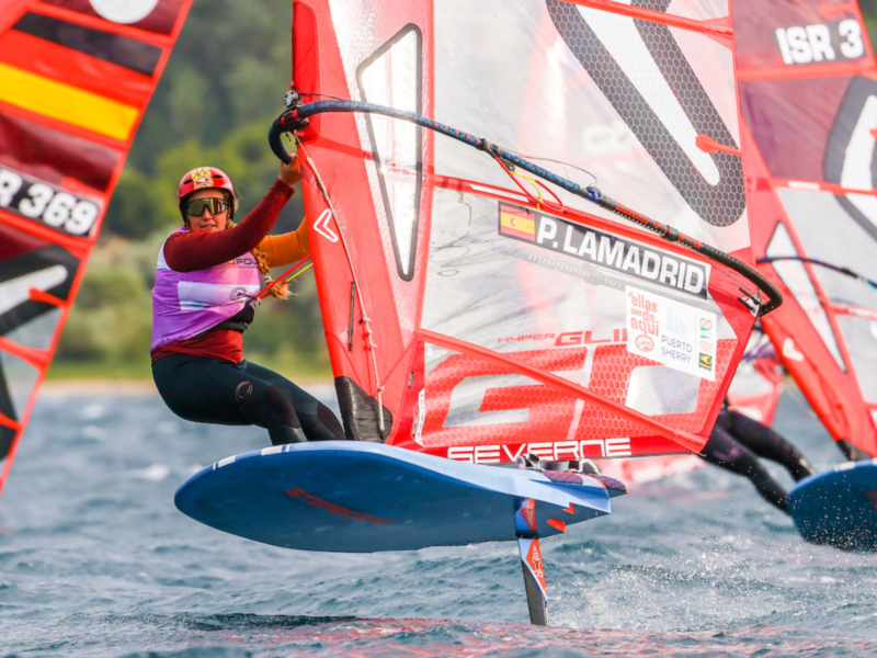 Competidor en windsurf durante una carrera, mostrando habilidad y concentración en el agua.