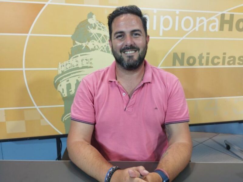 Entrevista en un estudio de noticias con fondo de logo y mesa de trabajo