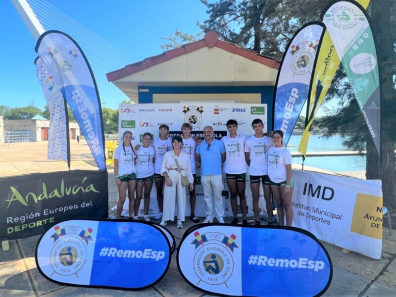 Equipo de remo celebrando un éxito en la Región Europea del Deporte, con banners y logotipos de instituciones locales.