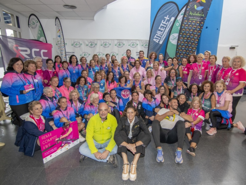 Grup de dones vestides amb camises rosa i pantalons negres posant per a una foto de grup. Al fons, hi ha banners amb el logotip d'ACB i una pancarta rosa amb la inscripció "RCC". La imatge es troba en un espai interior amb elements decoratius i lluminosos.