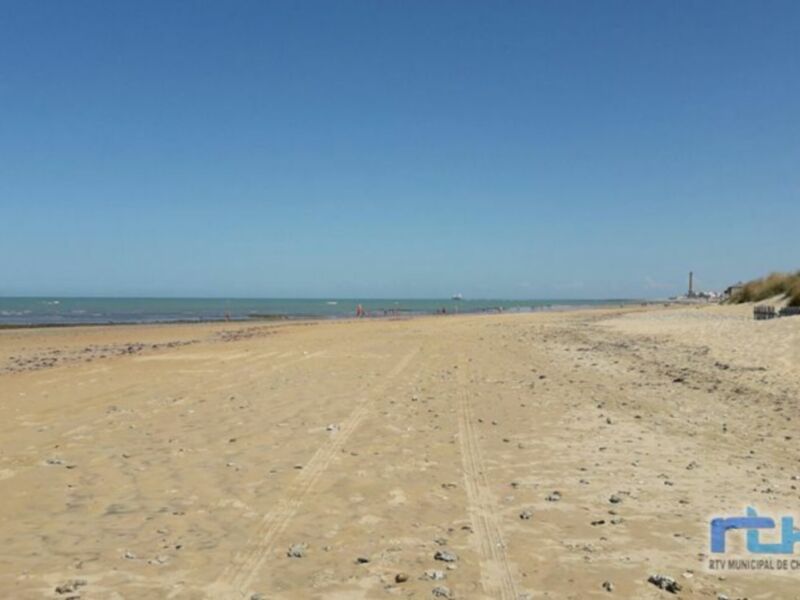 Playa desierta con un horizonte azul claro y pequeñas rocas en el suelo.