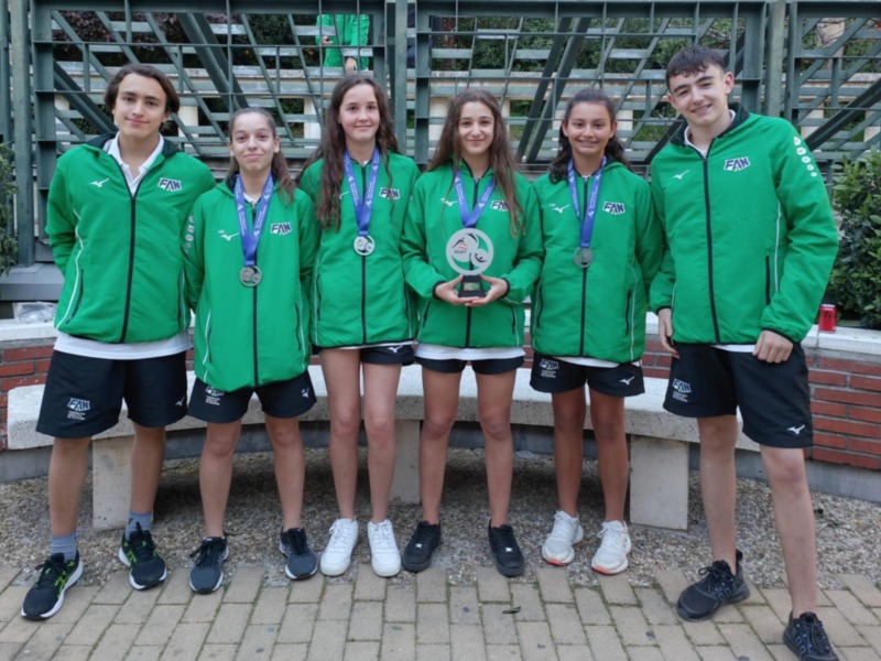 Equipo de atletas posando con sus medallas y trofeo en un evento deportivo.