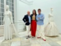 Tres personas posan frente a dos maniquíes con vestidos de novia en un entorno blanco y elegante.