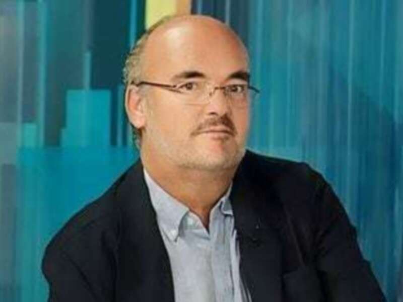 Un hombre con gafas y una camisa azul, posiblemente en un programa de televisión o conferencia.