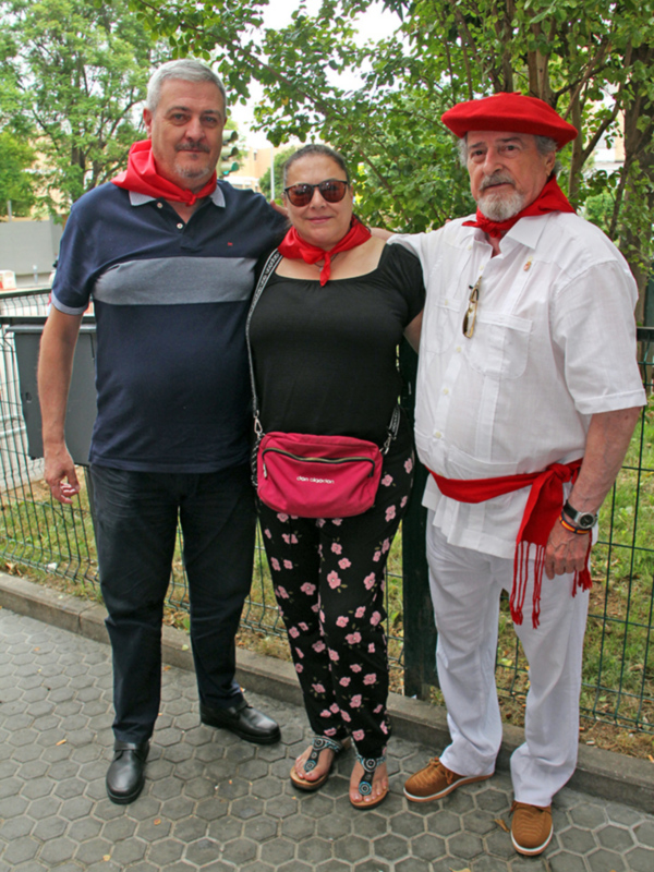 Tres personas posando en una calle con árboles al fondo.