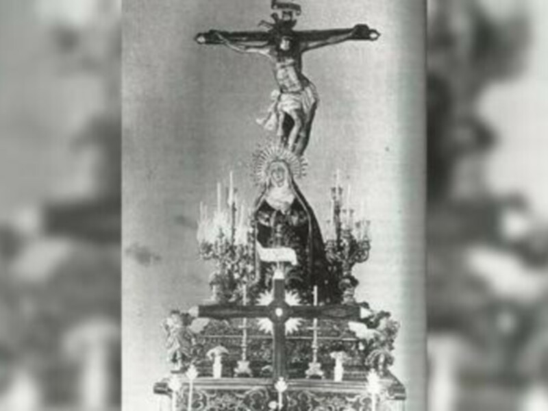 Imagen histórica de la procesión de la Virgen de la Esperanza en Sevilla, España, con la imagen de la Virgen en el centro y la Cruz de Cristo en la parte superior.