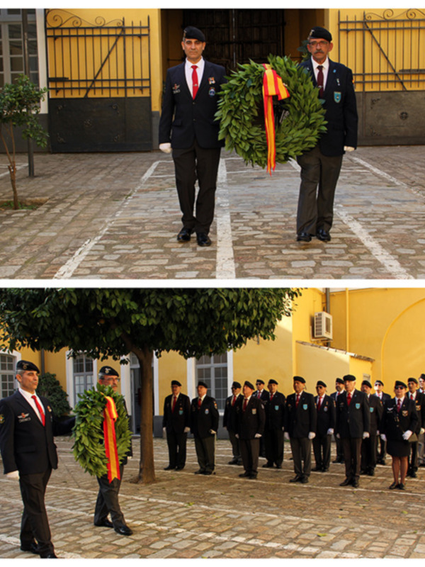 Oficiales militares en ceremonia con guirnalda y uniformes formales en patio de edificio amarillo.