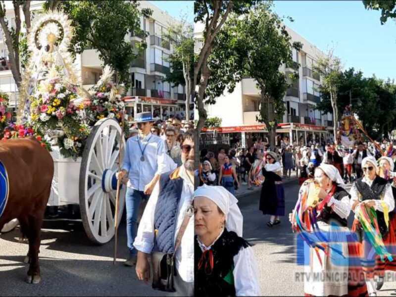 Desfile tradicional en Palma de Mallorca, con personas vestidas con trajes típicos y una carroza decorada con flores.
