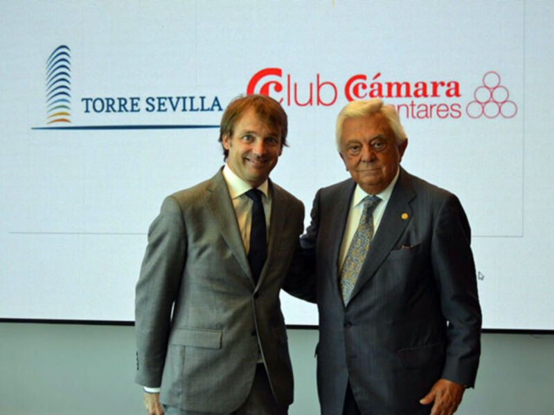 Dos hombres en trajes posan juntos en la Torre Sevilla, Club Cámara de Comercio.