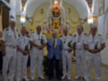 Un grupo de oficiales militares en uniforme blanco posa frente a una imagen religiosa, probablemente durante un evento oficial.