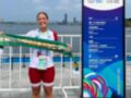 Una atleta sonriente sostiene un cinturón de Club Náutico mientras posa frente a una señal informativa del World Games 2025 en Chengdu.