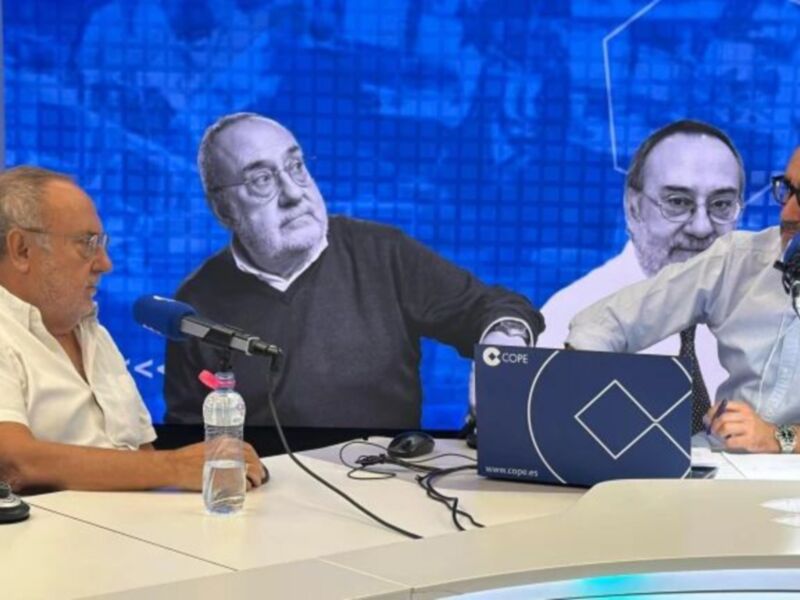 Se observa a tres personas sentadas en una mesa de conferencia, con micrófonos y un monitor en el fondo que muestra a dos personas más. La escena parece ser parte de una transmisión o entrevista en vivo, posiblemente un debate político.