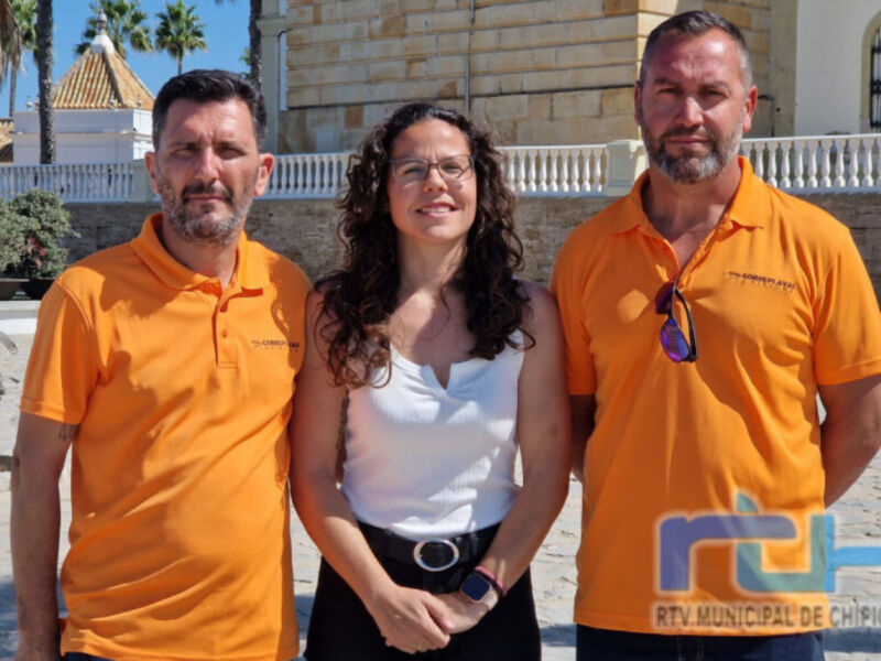 Tres personas posando frente a una estructura con columnas, uno de ellos con gafas colgadas en el cuello. La imagen está firmada por "RTV.MUNICIPAL.DE.CHIPIONA".