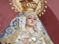 Imagen de una Virgen María vestida con un manto negro y dorado, portando una corona de oro y un halo estrellado. La Virgen sostiene el Sagrado Corazón en su mano izquierda, y su rostro está cubierto por una capa blanca con detalles dorados. La imagen se encuentra en un contexto religioso, posiblemente dentro de una iglesia o templo.